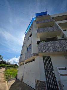 a white building with a gate and a garage at Apartamento familiar, tranquilo in Curití +3 photos