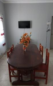 a wooden table with a vase of flowers on it at Casa del Arbol in San Fernando del Valle de Catamarca