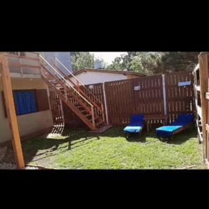 two blue chairs and a staircase in front of a fence at Mí esquina departamentos familiares in Villa Gesell