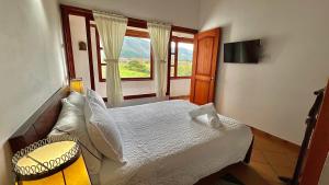 ein Schlafzimmer mit einem Bett und einem großen Fenster in der Unterkunft Refugio Khalma de la Montaña in Villa de Leyva