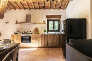 Una cocina con gabinetes de madera y un refrigerador negro. en Historic Apartment With San Gimignano Hills View, en Villa del Monte