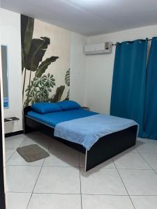 ein Schlafzimmer mit einem Bett mit blauer Bettwäsche und einem blauen Vorhang in der Unterkunft Blue Apartments in Willemstad
