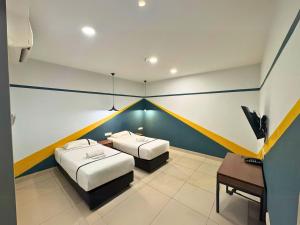 a room with two beds and a desk in it at Smile Hotel Klang Bukit Tinggi in Kampong Telok Gadong Besar