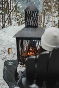 una persona seduta davanti a un fuoco nella neve di Zen House 7 - Villas & Spa a Morin-Heights