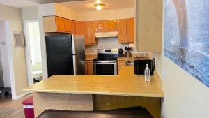 eine Küche mit Holzschränken und einem schwarzen Kühlschrank in der Unterkunft Midnight Sun - Near Airport and Shopping in Anchorage