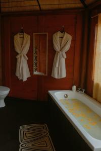 a bathroom with a tub and a mirror and towels at African Hut Camp - Free Massage With Sauna And Hot Tub in Tulbagh