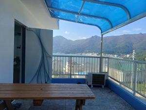 a balcony with a wooden table and a view of the mountains at Melodia Pension in Geoje
