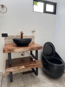 a bathroom with a black sink and a toilet at Sempiterno- la cabaña Whispering Wind in La Vega