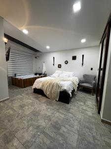 a bedroom with a large bed and a chair at Sempiterno- la cabaña Whispering Wind in La Vega