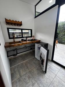 a kitchen with a counter and a sink and a refrigerator at Sempiterno- la cabaña Whispering Wind in La Vega