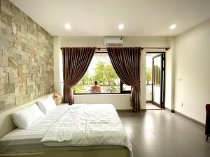 a bedroom with a large bed and a large window at Aura Beachfront Hotel - Apartment in Da Nang