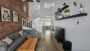 a living room with a couch and a tv at Emerald Break- The Perfect Coastal Escape in Emerald Beach
