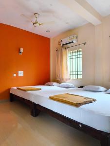 1 Schlafzimmer mit 2 Betten und einer orangefarbenen Wand in der Unterkunft Kamath regency and cottages in Dharmastala