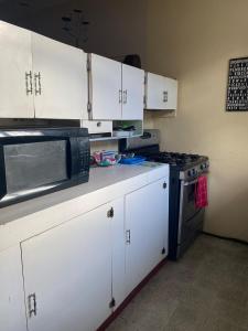 a kitchen with white cabinets and a microwave and a stove at Secure charming 1-bedroom house in Port-of-Spain