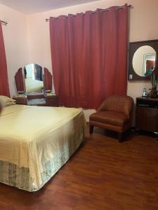 a bedroom with a bed and a chair and a mirror at Secure charming 1-bedroom house in Port-of-Spain