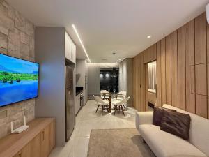 a living room with a couch and a television on a wall at Studio Soberano - O mais luxuoso de CG in Campo Grande