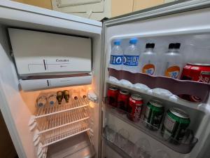 an open refrigerator filled with soda and coke bottles at Aluguel temporada in Ouro Preto +19 photos