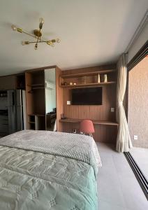 a bedroom with a bed with a television and a window at Studio Fortal in Fortaleza