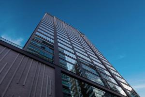 a tall glass building with a blue sky in the background at Flat Infinity 1504 Vista Mar in Itapema