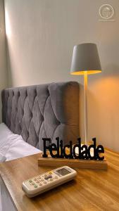 Un control remoto sobre una mesa al lado de una cama en Recanto da Mary em Morro de São Paulo no Centro e Próximo a Praia, en Morro de São Paulo