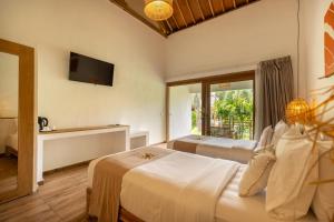 a hotel room with two beds and a television at Nativo Lombok Hotel in Kuta Lombok