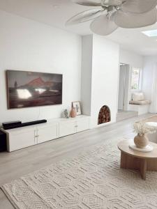 een witte woonkamer met een plafondventilator en een tafel bij The Summer House in Long Jetty