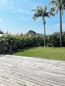 een houten terras met een bank en palmbomen bij The Summer House in Long Jetty +24 foto's