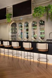 a bar with white chairs and a counter with bottles at Flat Infinity 1504 Vista Mar in Itapema