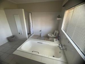 a white bathroom with a tub and a toilet at Kremetart Villa in Alldays +42 photos