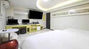 a room with a bed and a tv and a table at Jeonju COJAJA in Jeonju