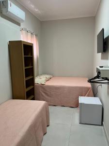 a small room with two beds and a tv at Pousada Luz do Sol in Piranhas