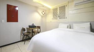 a white bedroom with a bed and a table at Jeonju COJAJA in Jeonju
