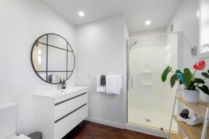 a white bathroom with a shower and a mirror at Beach Studio - coastal escape near Fitzroy Beach in New Plymouth
