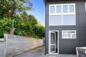 a gray house with a door and a fence at Beach Studio - coastal escape near Fitzroy Beach in New Plymouth