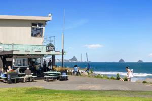 people sitting on benches in front of a building at the beach at Beach Studio - coastal escape near Fitzroy Beach in New Plymouth +12 photos