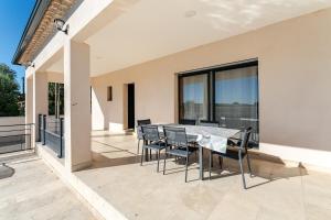 a patio with a table and chairs on a balcony at L'Oasis de Saint-Quentin in Saint-Quentin-la-Poterie
