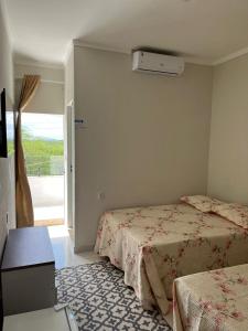 a bedroom with two beds and a window at Pousada Luz do Sol in Piranhas