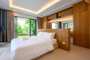 une chambre avec un grand lit et une grande fenêtre dans l'établissement New Luxury Pool Villa Bangtao Free Electricity & Daily Cleaning, à Ban Pak Lak 47 autres photos