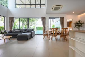 un salon avec un canapé, une table et des chaises dans l'établissement New Luxury Pool Villa Bangtao Free Electricity & Daily Cleaning, à Ban Pak Lak