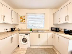 a kitchen with white cabinets and a washer and dryer at Quite Contractor Stay with Private Driveway in Hartlepool +17 photos