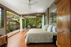 ein Schlafzimmer mit einem Bett und einem großen Fenster in der Unterkunft Mullum Cottage 10 minutes from beaches in Mullumbimby
