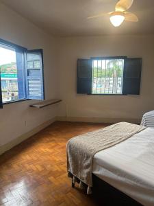 a bedroom with two beds and two windows at Oxx Quarto Terra in Congonhas +8 photos