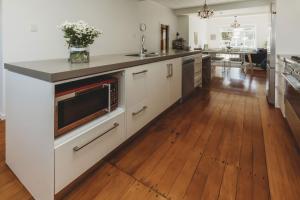 une cuisine avec des armoires blanches et un plancher en bois dans l'établissement Ropiha Retreat - close to Fitzroy Beach paradise, à New Plymouth 11 autres photos