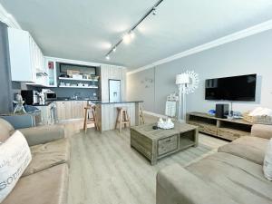 een woonkamer met een bank en een tafel bij Coastal Hospitality - Beach Club 205 in Mosselbaai