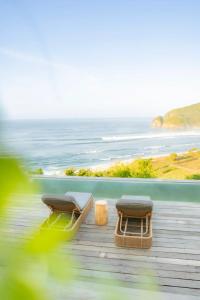 two chairs and a table on a deck with the ocean at Elysian Cove - One Bedroom Villa in Sekongkang Bawa