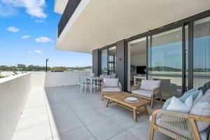 a patio with a couch and chairs on a balcony at 409 at CODA - City Convenience Meets Coastal Ease in Coffs Harbour