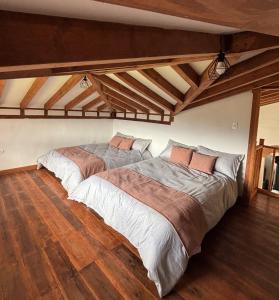 two beds in a large room with wooden floors at Chalet Villa Serena in Villa de Leyva