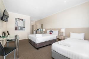 a hotel room with two beds and a desk at Mildura Riverview Motel in Gol Gol