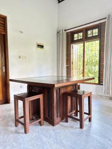 a large wooden table with two stools in a room at Calm Casita Luxury Villa in Matara in Matara