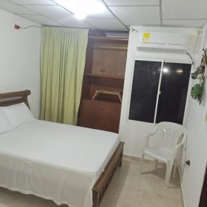 a bedroom with a bed and a chair and a window at Donde Mire in Puerto Colombia